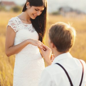 male-putting-engagement-ring-on-woman-hand-outdoors-in-a-golden.jpg